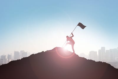 Person raising a flag on a summit